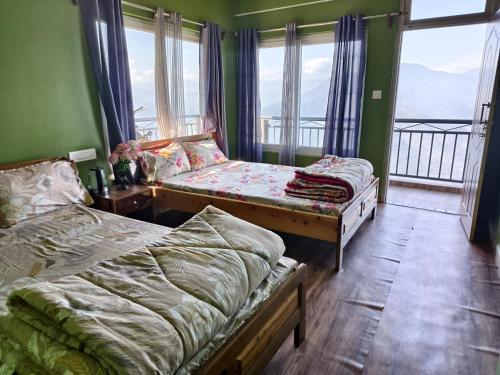 a bedroom with two beds and a balcony at Petratos Homestay in Kalimpong