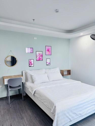 a white bedroom with a bed and a chair at Khách Sạn Diamond Hotel Văn Giang Hưng Yên in Cửu Cảo