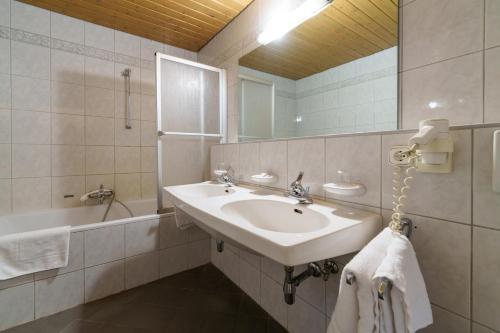 ein Badezimmer mit Waschbecken, Badewanne und Spiegel in der Unterkunft Altstadthotel Eck in Lienz