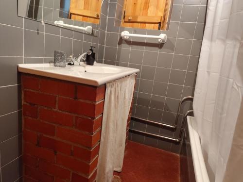 a bathroom with a sink and a brick wall at Costas Guests in Sardoal