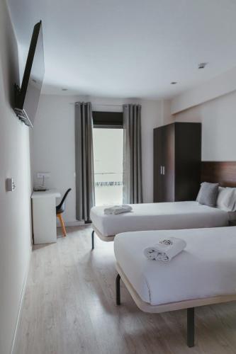 a hotel room with two beds and a window at Imprenta Musical Alojamiento in Astorga