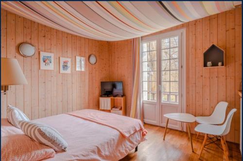 a bedroom with a bed and a table and a window at Maison d'hôtes Il était une fois in Pont-lʼÉvêque