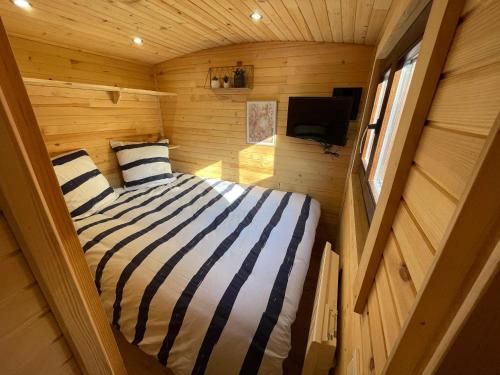 a small bedroom with a bed in a wooden cabin at La Verdine Lodge & Spa in Romorantin