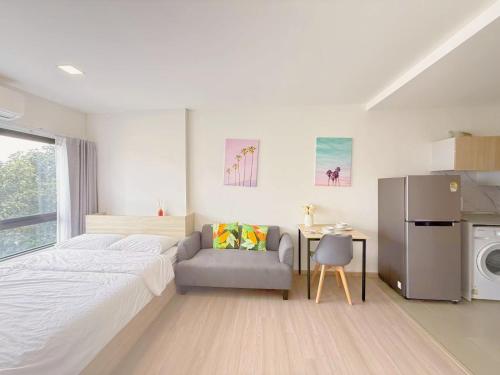 a bedroom with a bed and a chair and a table at Vay 1 Pattaya Downtown Cozy Condo in North Pattaya