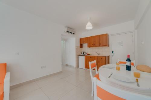 a white kitchen with a table and chairs and a counter top at Christos Napa Self Serviced Apartments in Ayia Napa