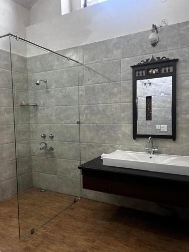 a bathroom with a sink and a glass shower at VANVASA RESORTs in Kānda