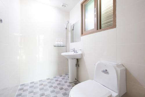 a white bathroom with a toilet and a sink at Suncheon Bay Ecology Pension in Suncheon