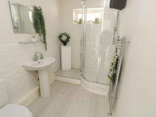 a white bathroom with a shower and a sink at Sunset Sands in Deganwy