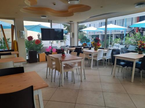 a restaurant with tables and chairs and a flat screen tv at Hotel Mirage in Rimini