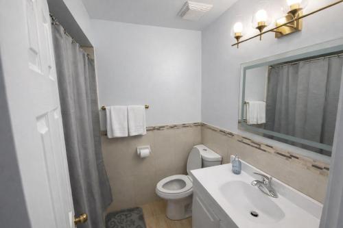 a bathroom with a sink and a toilet and a mirror at Newly Renovated 3BR North York Bungalow with Backyard Patio & Volleyball Set! Close to Rogers Stadium, TTC Subway Access, Perfect for Family Travel, Group Trips & Work Stays! in Toronto