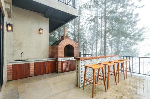 an outdoor kitchen with stools and a grill on a balcony at Altitude Ambuluwawa in Gampola