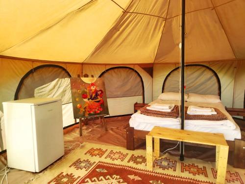 a tent with a bed and a table in it at La Busuri Camp in Roşia