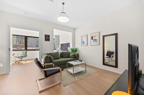 a living room with a green couch and a mirror at Central Emporium Hotel-Style 1BR with King Bed in Melbourne