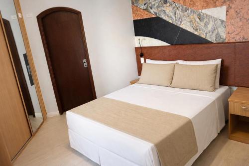 a bedroom with a large white bed in a room at Hotel Cosmopolitan Praia Flat in Santos