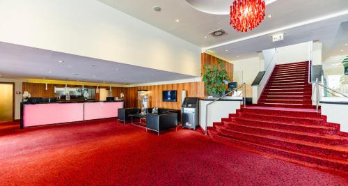 eine mit rotem Teppich ausgelegte Treppe in einem Gebäude mit rotem Teppich in der Unterkunft PLAZA INN Wels in Wels