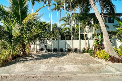 a driveway with palm trees and a white fence at Art Deco Apt w Pool One Mile to Beach Pets Welcome in Lake Worth