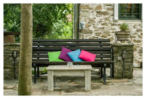 a park bench with two colorful pillows and a table at Archontiko Stamou in Zagora