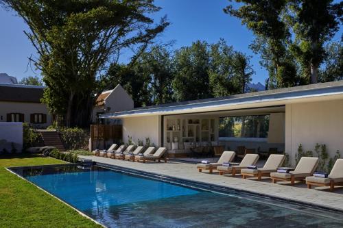 a swimming pool with lounge chairs next to a house at Blaauwklippen Manor by NEWMARK in Stellenbosch