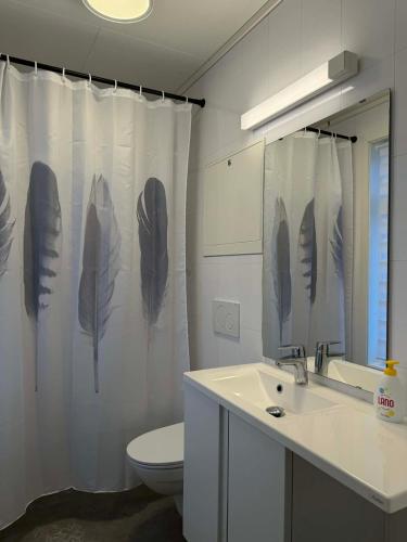 a bathroom with a shower curtain with feathers on it at Davik Fjordparadis in Bakken