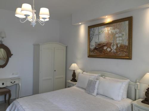 a bedroom with a white bed with a painting on the wall at The White Suites in Adamas