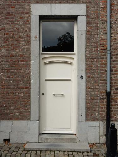 a white door in a brick building with a window at Besselaar Apartments in Maastricht