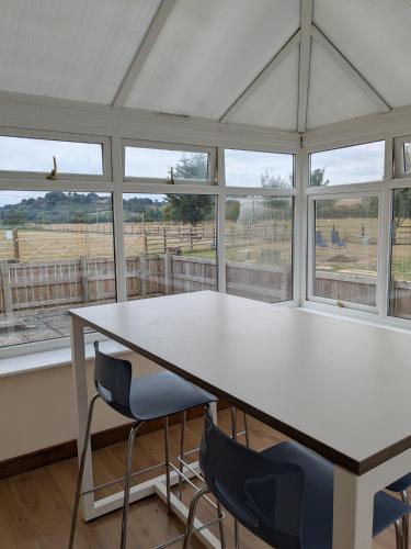 a white table and chairs in a room with windows at Tanyfford Lodge, Abermule, Mid Wales, SY15 6NT in Abermule