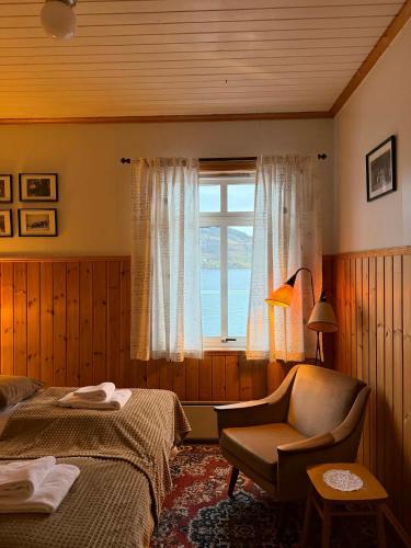 a bedroom with a bed and a chair and a window at Davik Fjordparadis in Bakken