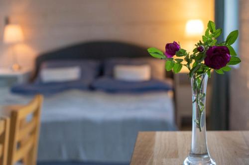 a vase with flowers on a table in a bedroom at Lawendowe Pole - Domek Różany in Nowe Kawkowo