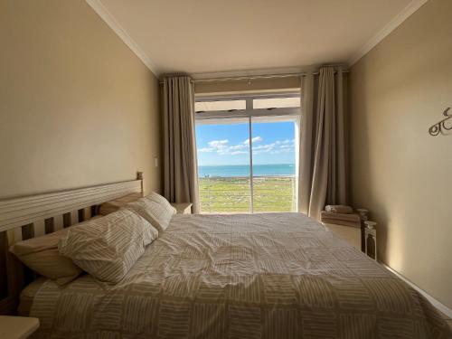 a bedroom with a bed and a large window at Boardwalk 11 in Struisbaai