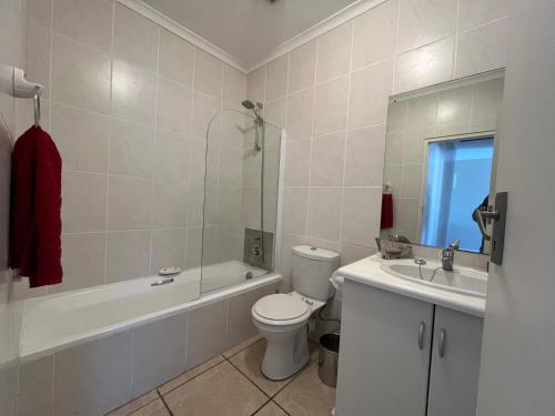 a bathroom with a toilet and a tub and a sink at Boardwalk 11 in Struisbaai