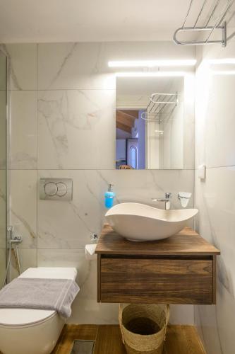 a bathroom with a sink and a toilet and a mirror at Voidοkilia rooms in Petrochori