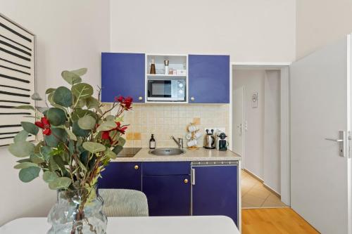 a kitchen with blue cabinets and a vase with red flowers at Bright City Hideaway, Augarten and Danube - 5 min Metro - 10 min Center in Vienna