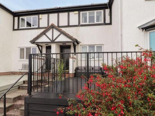 a house with a black fence and red flowers at Castle View in Deganwy