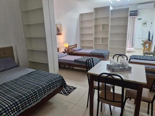 a room with three beds and a table and chairs at Flat Casa Grande in Itapira