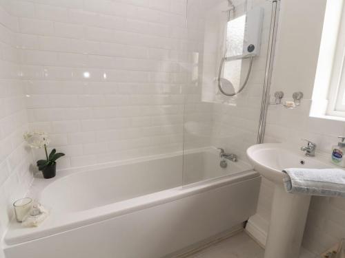 a white bathroom with a tub and a sink at Castle View in Deganwy