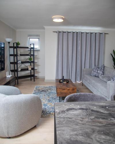 a living room with a couch and a table at Beachside Modern Holiday Apartments in Cape Town