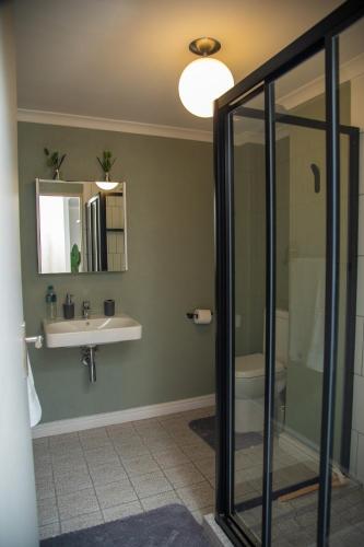 a bathroom with a shower and a sink and a mirror at Beachside Modern Holiday Apartments in Cape Town