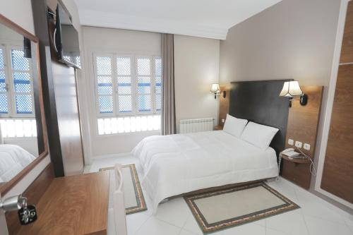 a bedroom with a white bed and two windows at Hotel karim Tunis in Tunis