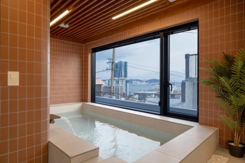 a bathroom with a tub with a view of the city at Staykor Busan in Pusan
