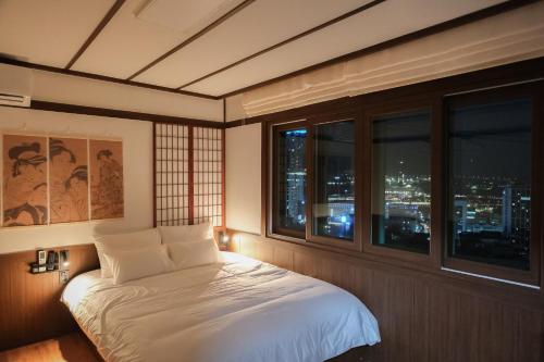 a bedroom with a bed with a view of the city at Staykor Busan in Pusan