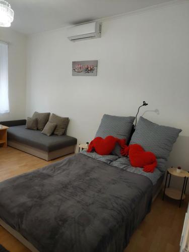 a bedroom with a bed with red pillows and a couch at Ánizs Apartmanház in Makó