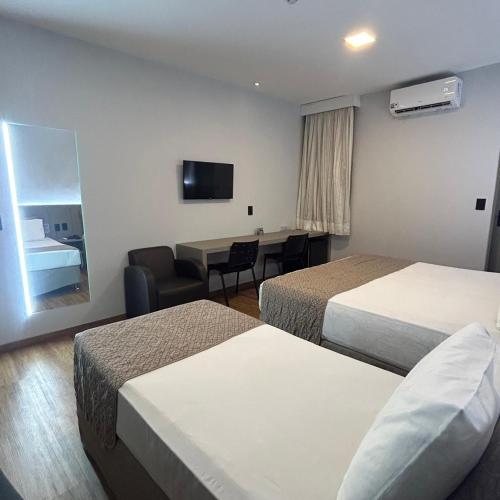 a hotel room with two beds and a desk at Hotel Maysa Caruaru in Caruaru