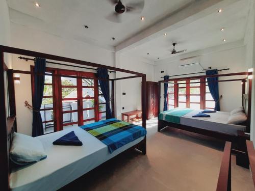 two beds in a room with two windows at Drift Bay in Arugam Bay