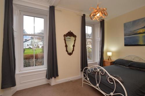 a bedroom with a bed and two windows at Secret Coast Getaway in Tighnabruaich