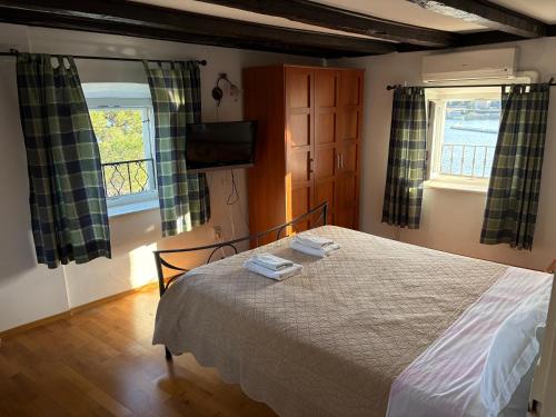 a bedroom with a bed and two windows at Apartments Tedeschi in Korčula