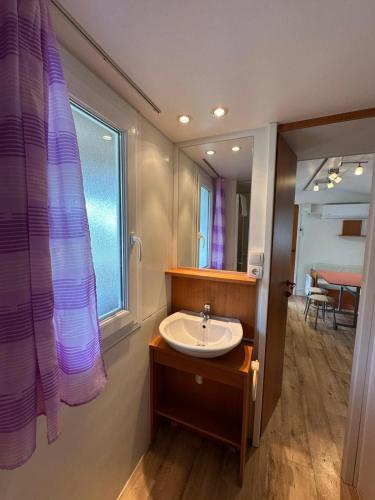 a bathroom with a sink and a window and a mirror at Camping Bi Village - Maeva Vacansoleil in Valbandon