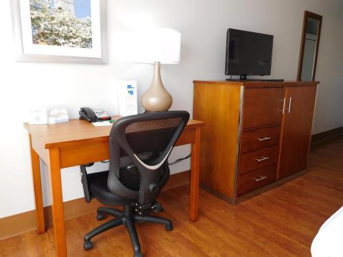 a room with a desk with a chair and a television at Wyndham Garden Greensboro in Greensboro