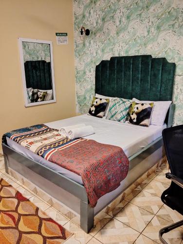 a bed with a green headboard in a room at MALKIA SUITEs in Diani Beach