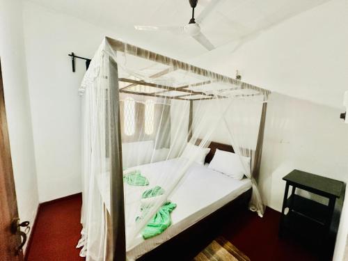 a bed with a canopy in a room at Long Beach Homestay in Tangalle