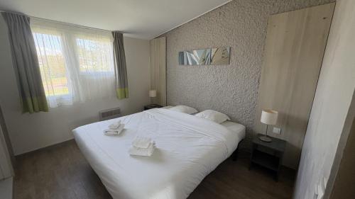 a bedroom with a white bed with two towels on it at VVF Cotentin Îles anglo-normandes in Portbail